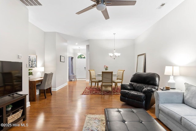 living room featuring ceiling fan with notable chandelier and hardwood / wood-style floors