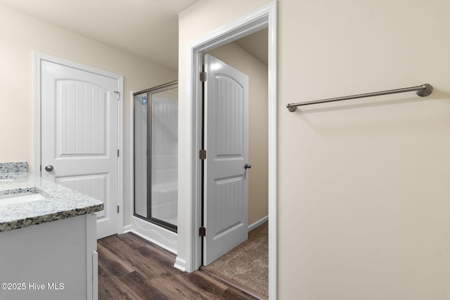 bathroom with wood finished floors, a shower stall, and vanity