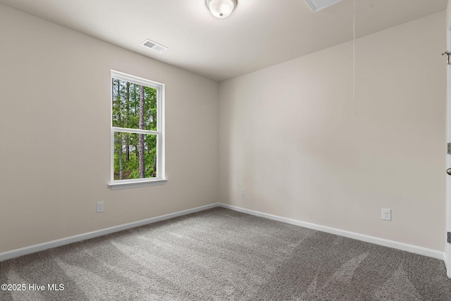 carpeted spare room with attic access, visible vents, and baseboards