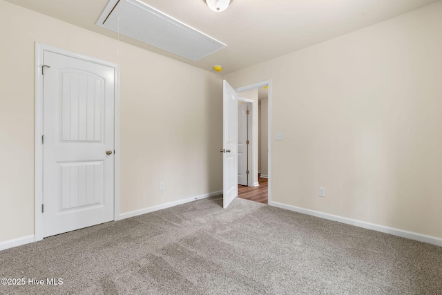 unfurnished bedroom featuring attic access, carpet, and baseboards