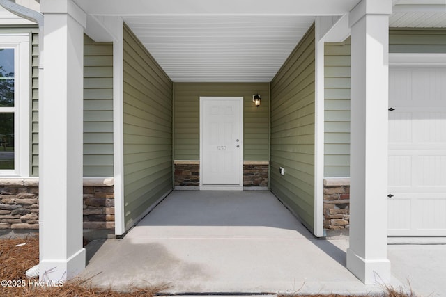 doorway to property featuring a garage and stone siding