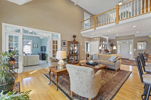 living room featuring light hardwood / wood-style floors, ceiling fan, and a high ceiling