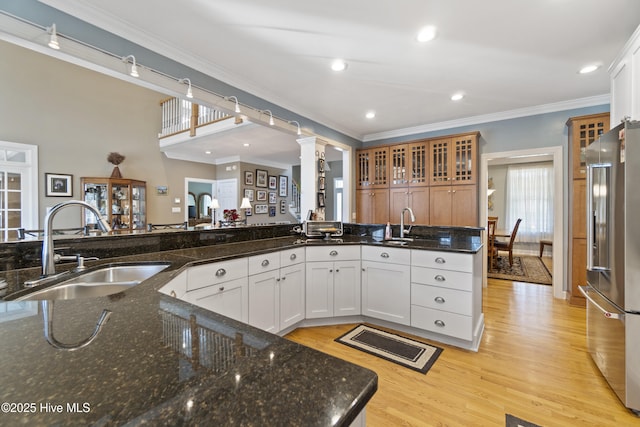 kitchen with sink, white cabinetry, crown molding, high end refrigerator, and dark stone countertops