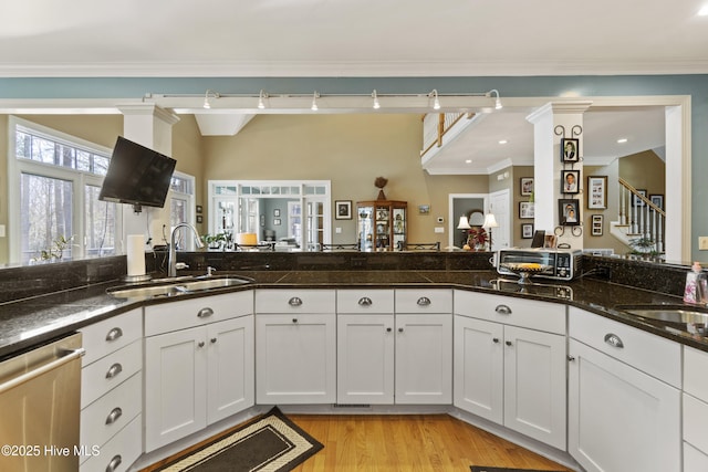 kitchen with white cabinetry, stainless steel dishwasher, sink, and dark stone countertops