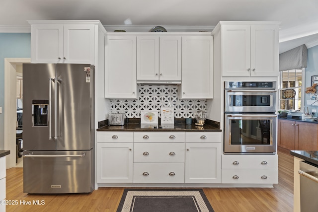 kitchen with white cabinetry, appliances with stainless steel finishes, dark stone countertops, and light wood-type flooring