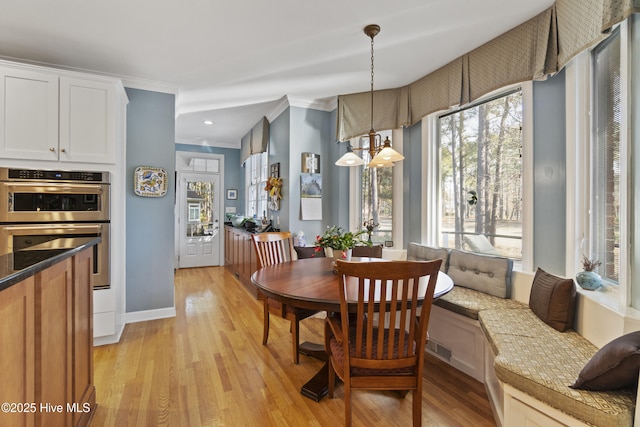 dining space with ornamental molding, light wood-type flooring, and breakfast area