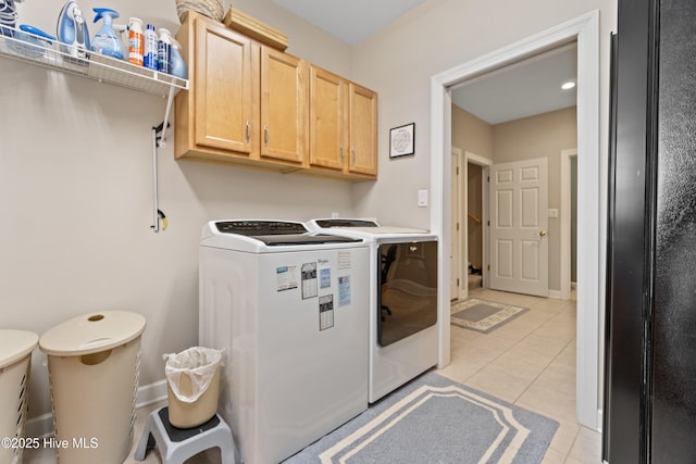 laundry area featuring separate washer and dryer, cabinets, and light tile patterned flooring