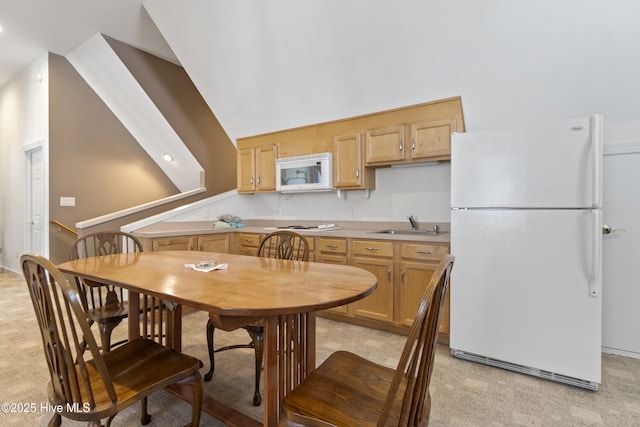 kitchen with white appliances, sink, and light carpet