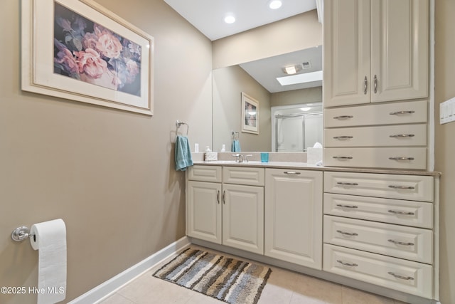 bathroom featuring tile patterned flooring, vanity, a skylight, and a shower with shower door