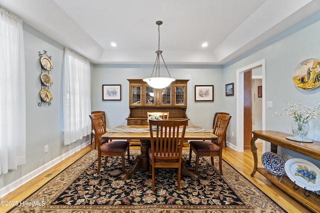 dining area featuring a tray ceiling and wood-type flooring