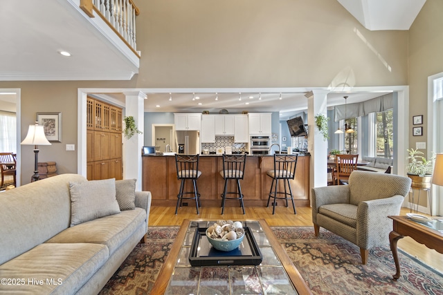 living room with plenty of natural light, light wood-type flooring, and ornate columns