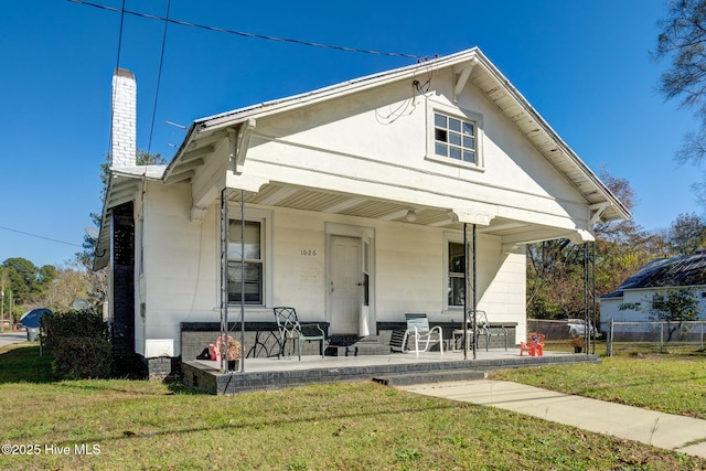 rear view of house featuring a yard and a porch