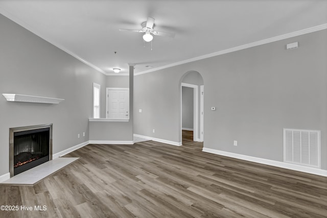 unfurnished living room with ceiling fan, ornamental molding, and wood-type flooring