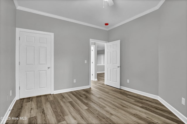 unfurnished bedroom featuring hardwood / wood-style flooring, ornamental molding, and ceiling fan