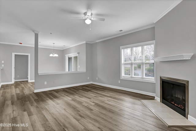 unfurnished living room featuring decorative columns, ornamental molding, ceiling fan with notable chandelier, and light hardwood / wood-style flooring