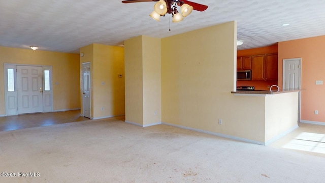 unfurnished living room with light carpet, ceiling fan, and a textured ceiling