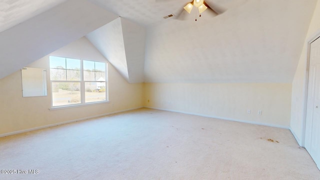 additional living space with ceiling fan, light colored carpet, and vaulted ceiling