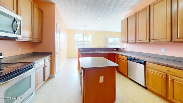 kitchen with sink, appliances with stainless steel finishes, a kitchen island, decorative light fixtures, and kitchen peninsula