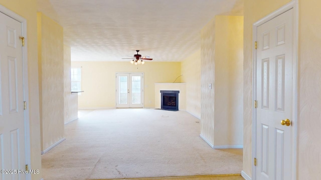 unfurnished living room featuring light colored carpet, ceiling fan, and french doors