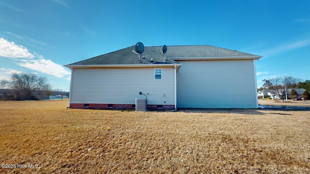 back of property featuring a yard and central AC