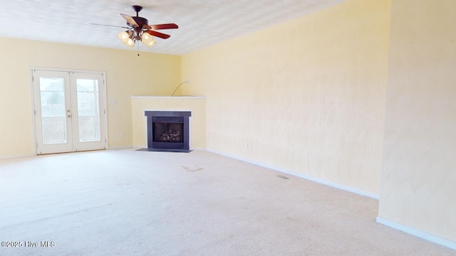 unfurnished living room with french doors, ceiling fan, and light carpet