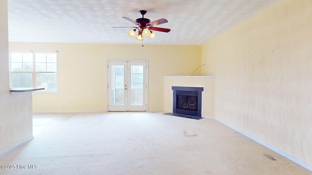 unfurnished living room with light carpet, plenty of natural light, french doors, and ceiling fan