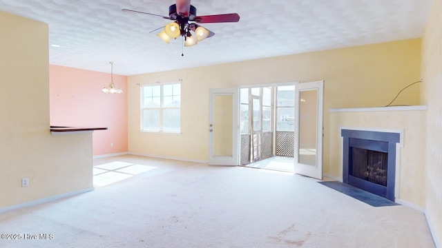 unfurnished living room featuring ceiling fan with notable chandelier, light carpet, and a textured ceiling