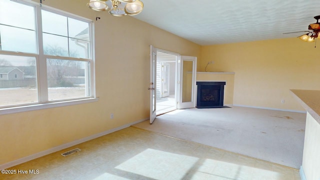 unfurnished living room featuring ceiling fan, carpet, and a textured ceiling