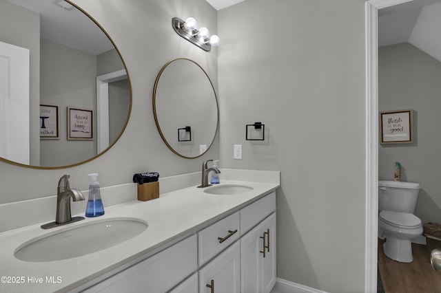 bathroom with hardwood / wood-style flooring, lofted ceiling, vanity, and toilet