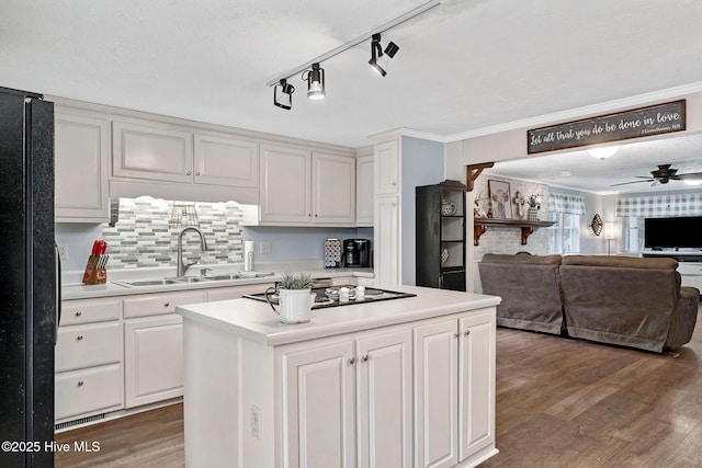 kitchen featuring light countertops, light wood-style flooring, white cabinets, a sink, and black appliances