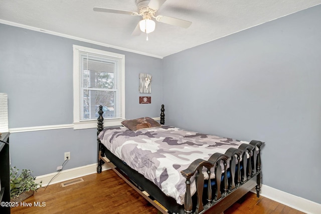 bedroom featuring baseboards, visible vents, ceiling fan, and wood finished floors