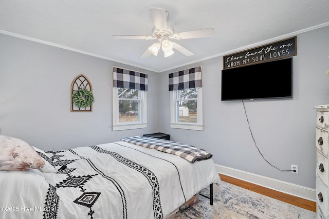 bedroom featuring ceiling fan, baseboards, crown molding, and wood finished floors