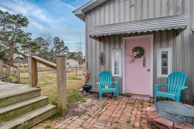 entrance to property with fence, board and batten siding, and a patio