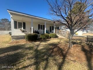 rear view of property with covered porch, fence, and a yard