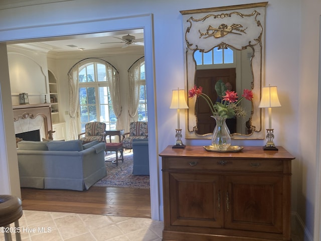 corridor featuring crown molding, light wood-type flooring, and built in shelves