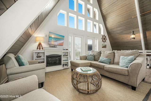 living room with wooden ceiling, high vaulted ceiling, and a glass covered fireplace