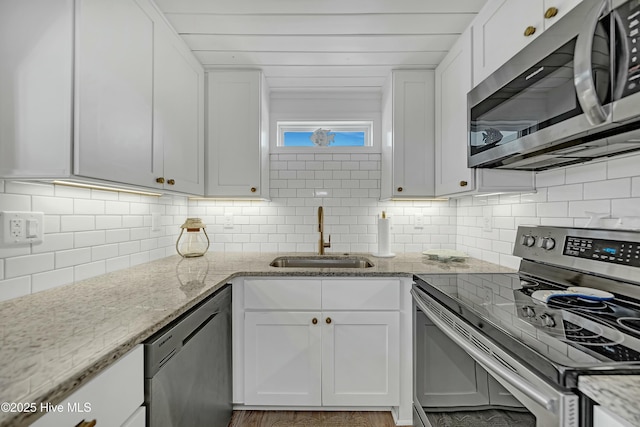 kitchen featuring decorative backsplash, appliances with stainless steel finishes, white cabinets, and a sink