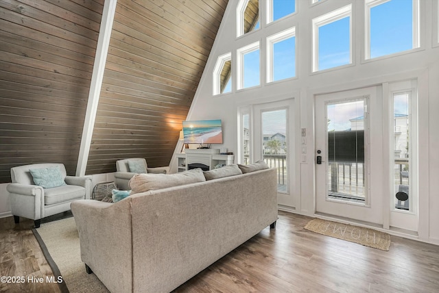 living room with a fireplace, wood walls, wooden ceiling, and wood finished floors