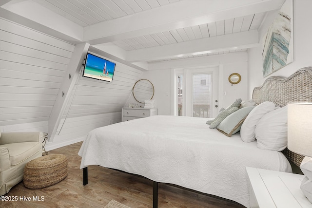 bedroom with wooden ceiling, wooden walls, wood finished floors, and beamed ceiling