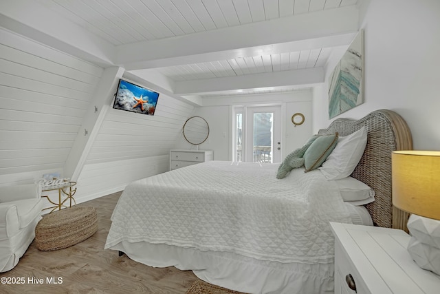 bedroom with beam ceiling, wood ceiling, wooden walls, wood finished floors, and access to outside