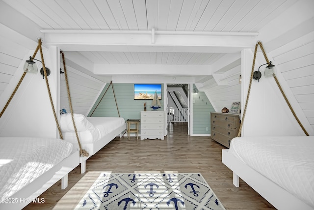 bedroom featuring beam ceiling, wooden ceiling, wood walls, and wood finished floors