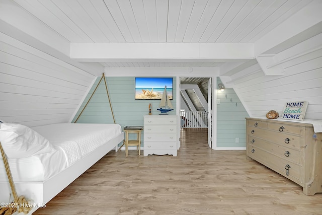 bedroom featuring vaulted ceiling with beams, wood ceiling, light wood-style flooring, and wooden walls