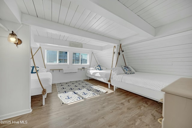 bedroom with wood ceiling, wood finished floors, beam ceiling, and wooden walls