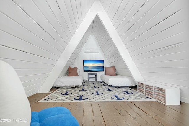 living area with lofted ceiling, hardwood / wood-style flooring, and wooden walls