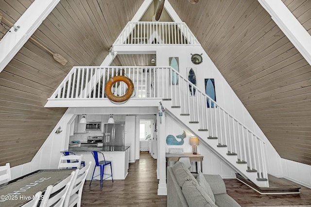 stairs with high vaulted ceiling, wood ceiling, and wood finished floors