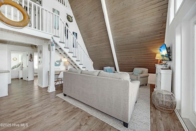 living area featuring light wood finished floors, stairway, a towering ceiling, and wooden walls