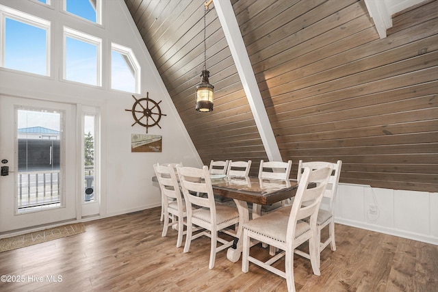 dining room with high vaulted ceiling, wooden ceiling, wood finished floors, and beam ceiling