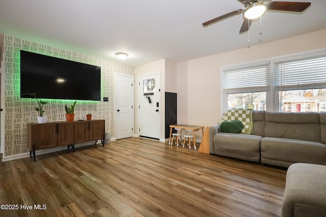 living area featuring wood finished floors, baseboards, and wallpapered walls