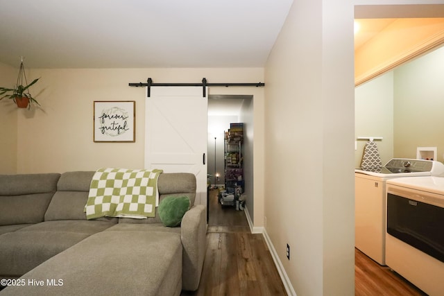 living room featuring wood finished floors, independent washer and dryer, baseboards, and a barn door