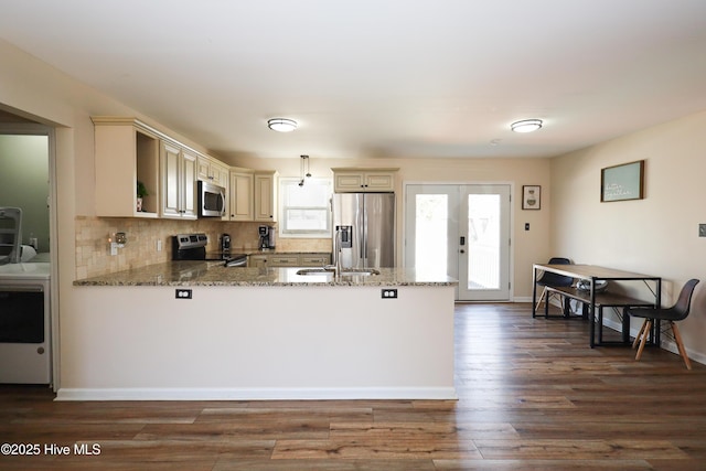 kitchen with stone counters, a peninsula, french doors, appliances with stainless steel finishes, and cream cabinetry